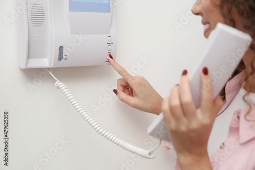 African-American woman pressing button on intercom panel indoors, closeup