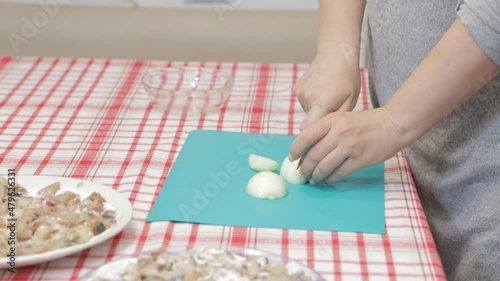 cuts onions for making Russian salad salad Shuba with herring, beetroot and boiled vegetables