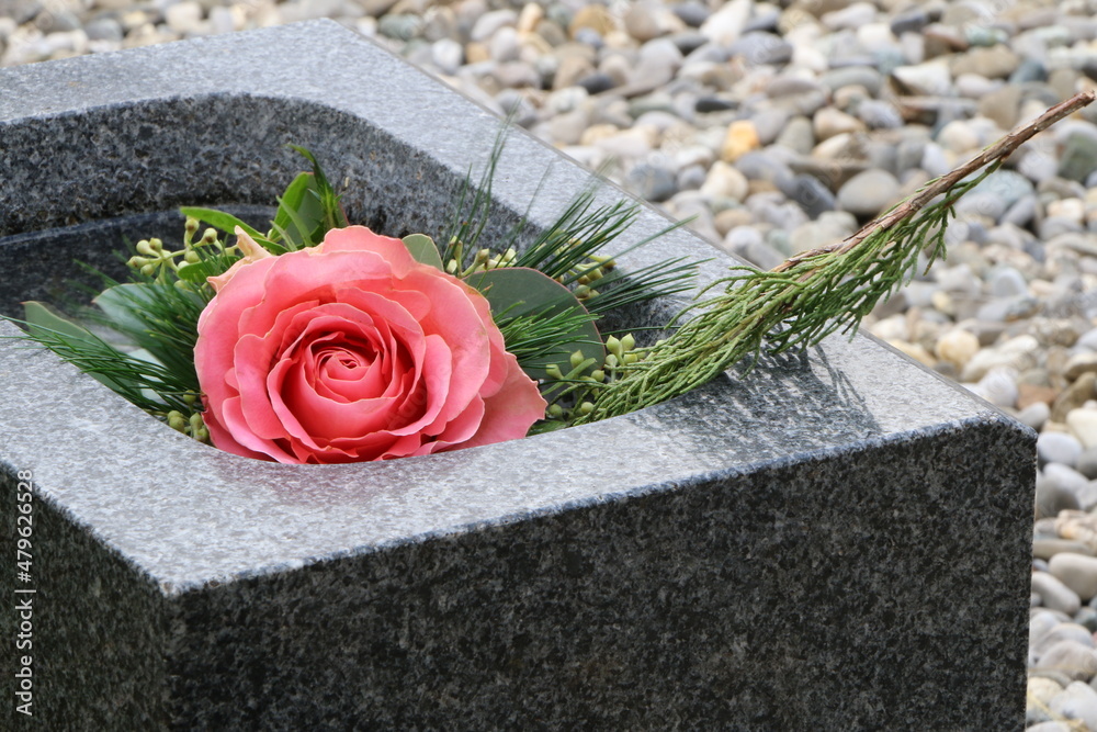 Eine Rose im Weihwasserkessel auf einem katholischen Friedhof in Österreich, eine Rose an einer Familiengrabstätte, Gedenken, Trauer, Tod