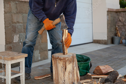 Man in jeans chopping wood in yard..