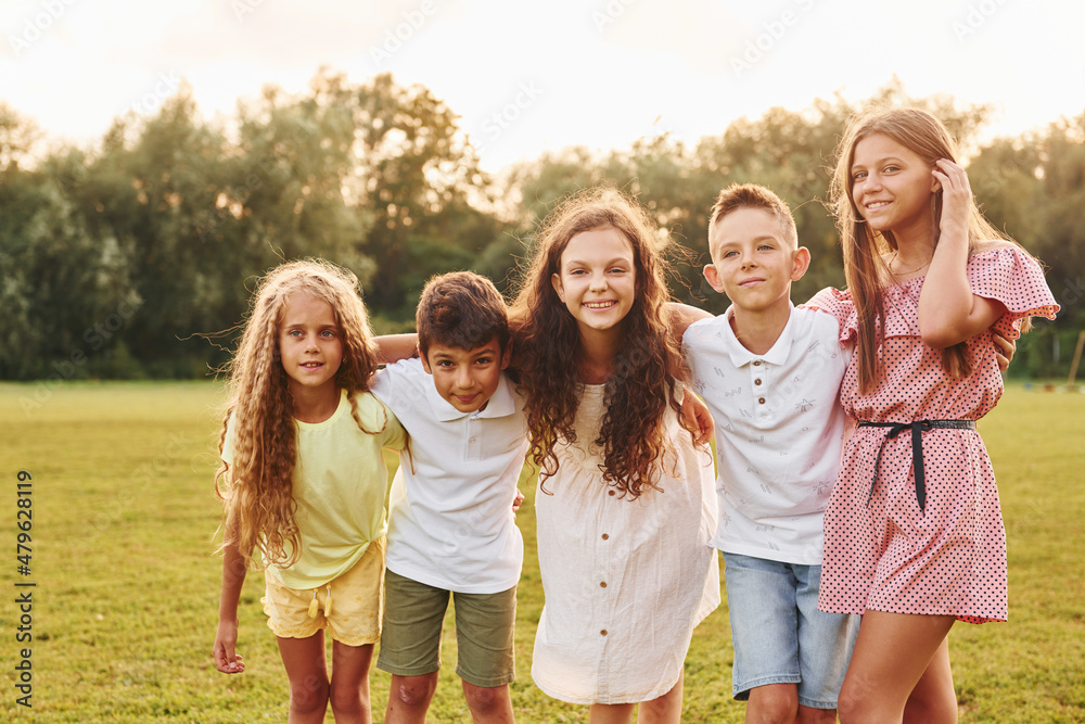 Having fun. Group of happy kids is outdoors on the sportive field at daytime Having fun. Group of happy kids is outdoors on the sportive field at daytime