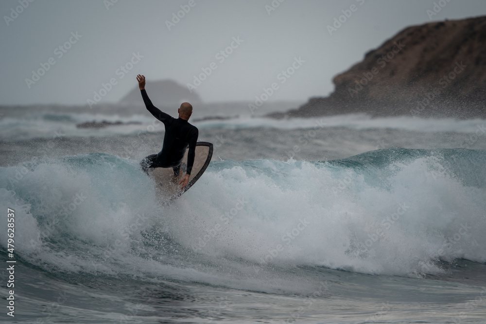 Senior man with black wetsuit, surfs a wave in Gran Canaria Senior man with black wetsuit, surfs a wave in Gran Canaria