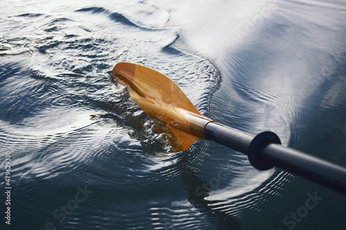 Oar paddles on calm water against the background of sunset rays, outdoor activities on a kayak, water sports