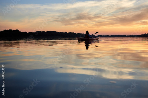 Sillouette of woman kayaking on river at golden sunset. Summer time, active recreation. Healthy lifestyle and care about mental health, resting in privacy and peace © watcherfox