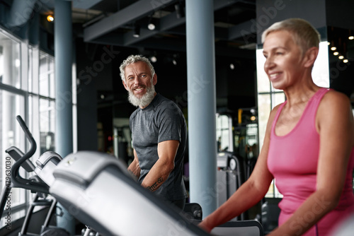 Seniors workout in gym. Smiling man looking at woman