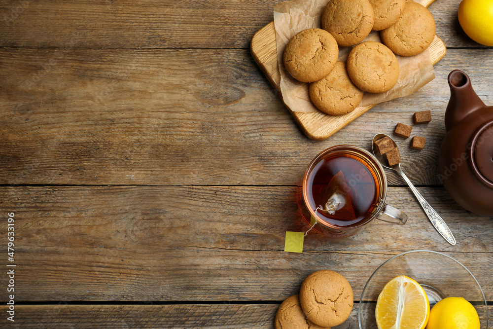 Flat lay composition with tea bag in glass cup of hot water on wooden table, space for text Flat lay composition with tea bag in glass cup of hot water on wooden table, space for text