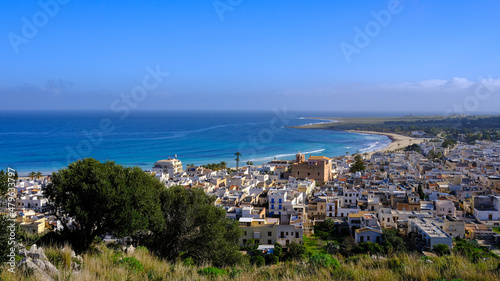 View of San Vito Lo Capo, Sicily, Italy. Sea, tree and empty beach. Houses and Church of San Vito.