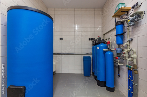 The interior of a modern gas boiler room with a blue tank and cylinders and various equipment. Water purification sistem photo
