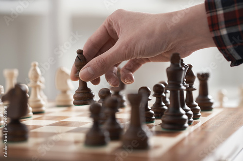 Moving a chess piece across the chessboard, making a chess move. An officer is holding a chess piece in his hand 
