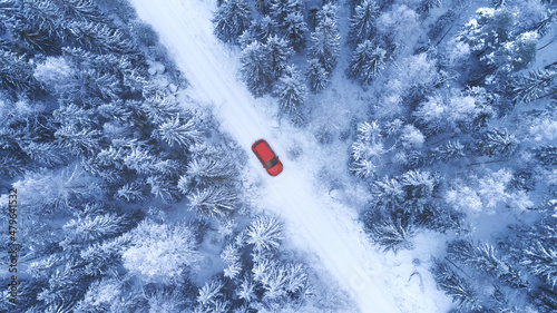 Country road going through the beautiful snow covered forest. Red car driving on winter road. Aerial view. Drone photography. © raland