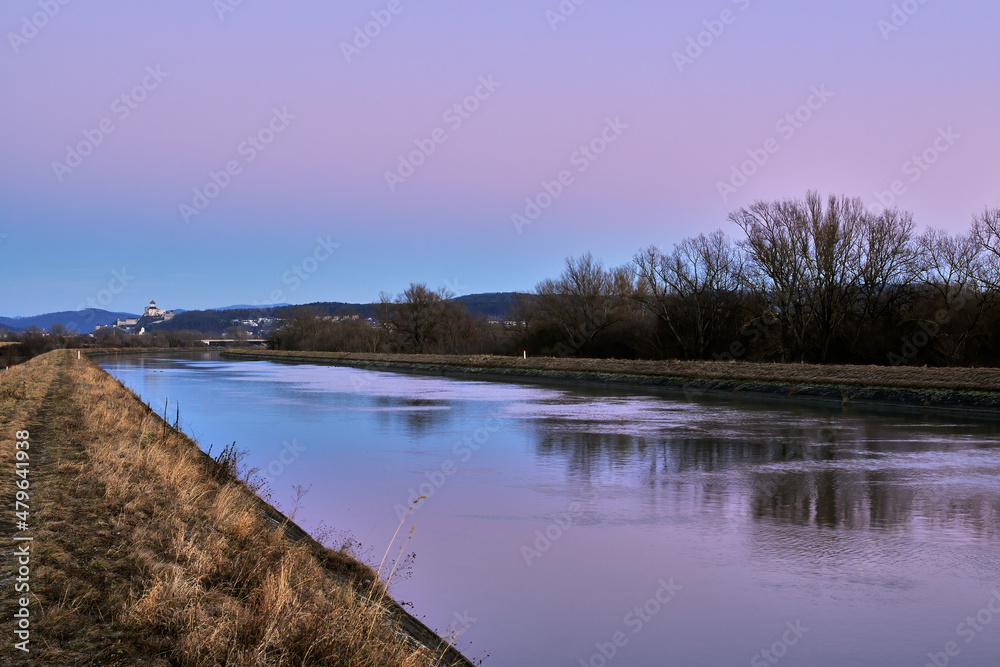 Early evening landscape with waterway shortly after sunset. Beautiful colored sky,  reflection on the surface. Trencin, Slovakia.