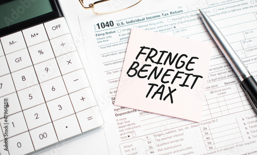 FRINGE BENEFIT TAX with pen, calculator, glass and sticker. Tax report sign