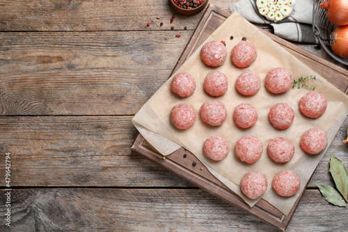 Many fresh raw meatballs on wooden table, flat lay Space for text