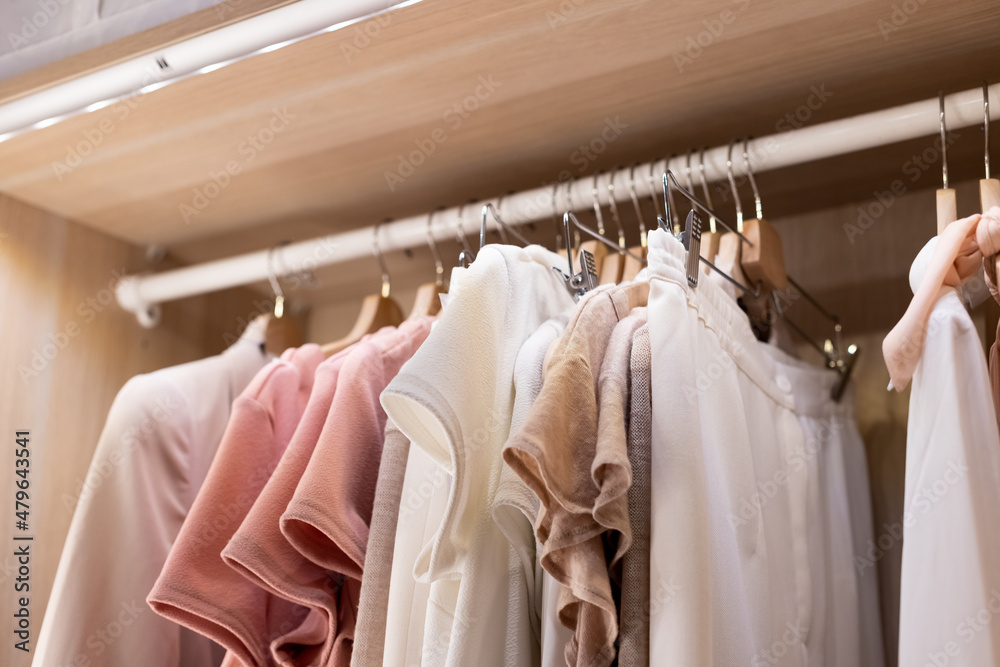 Clothes on a rail in a wardrobe. Seasonal capsule for easy dressing, order in things, cleaning out.Colorful casual clothes hang on hangers.Wardrobe, dressing room filled with clothes, shoes. storage