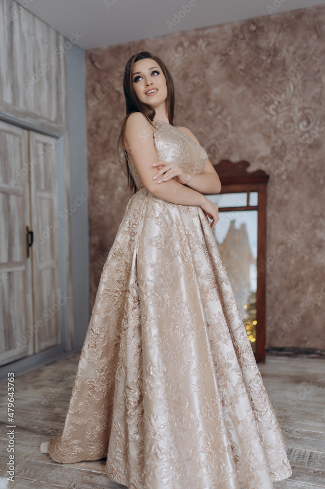 A beautiful girl in an evening dress smile shows a brick wall dress A beautiful girl in an evening dress smile shows a brick wall dress