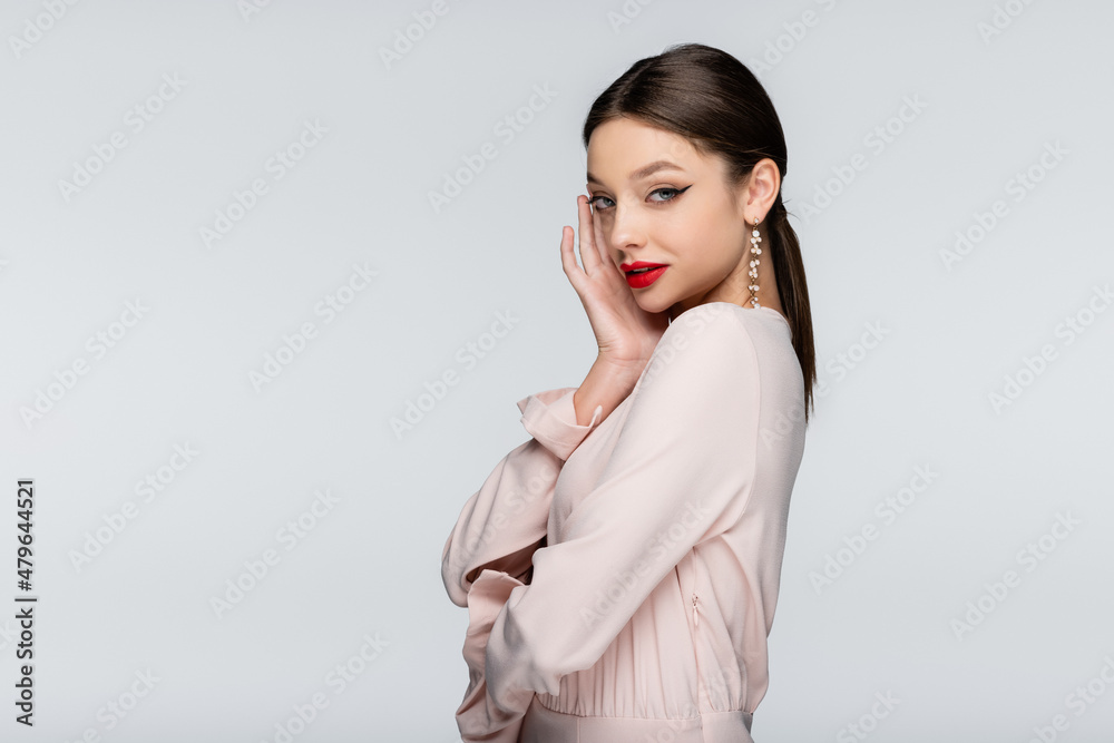 pretty woman in earrings and blouse looking at camera isolated on grey pretty woman in earrings and blouse looking at camera isolated on grey