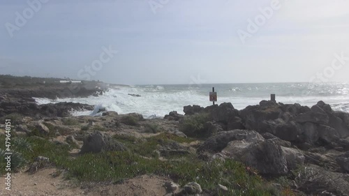 The waves of the Atlantic Ocean are breaking on the rocks, the volcanic coast of Gibraltar, the surf is breaking the waves on the rocks, white sea foam and salt spray, wind over the sea, high tide