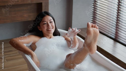 Asian Female Taking Bath With Foam Relaxing In Bathroom photo