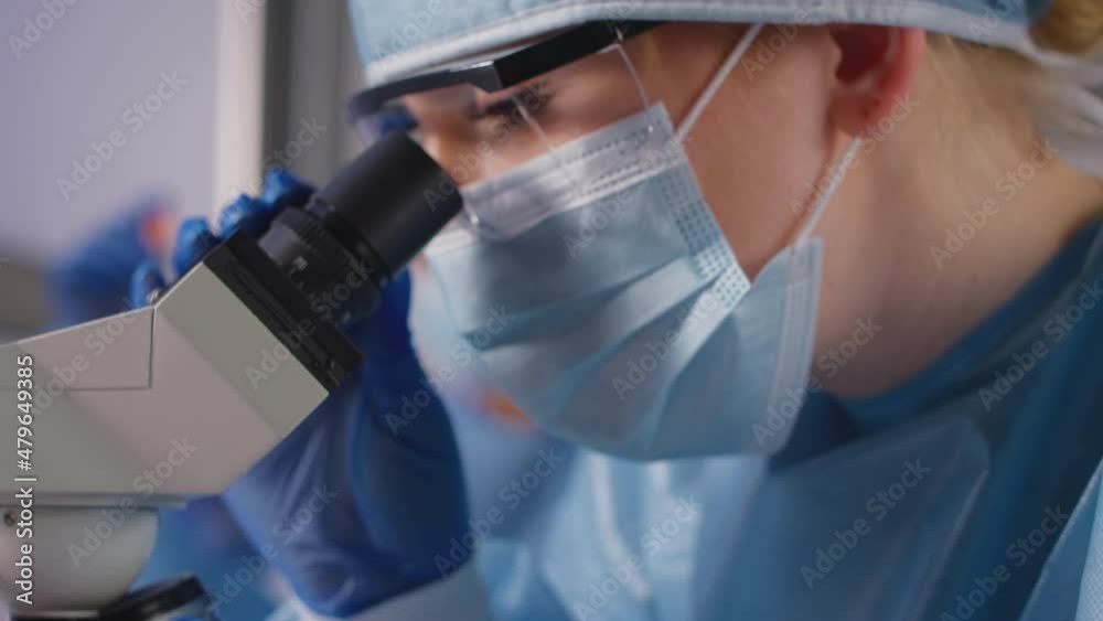 Female Lab Worker Wearing PPE Analysing Samples With Microscope Holding ...