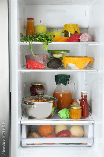 Open refrigerator with many different products packed in beeswax food wraps