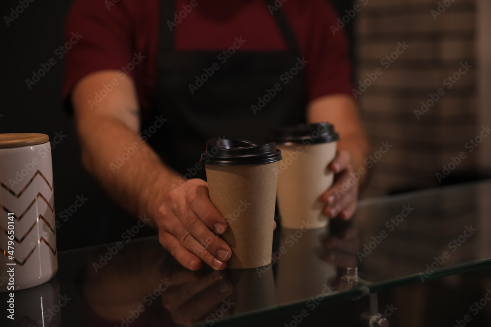 Barista putting takeaway coffee cups on glass table indoors, closeup