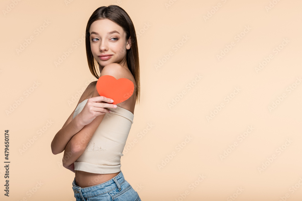 joyful woman in crop top holding red paper heart isolated on beige joyful woman in crop top holding red paper heart isolated on beige