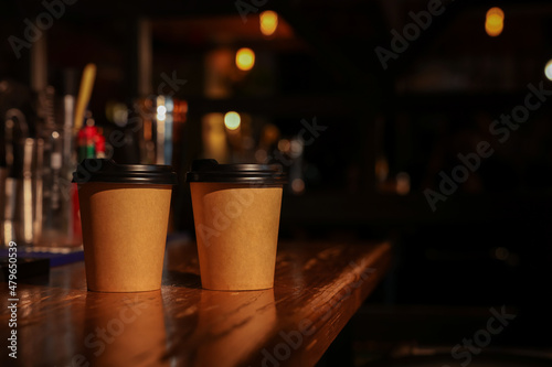 Paper coffee cups on wooden table in cafe. Space for text