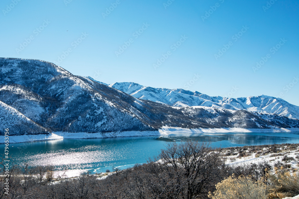 Snow-covered mountain with blue reservoir and blue sky with clouds