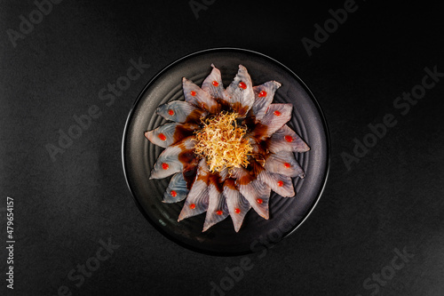 Fototapeta Naklejka Na Ścianę i Meble -  Fish carpaccio in a black plate with sweet potato straws.