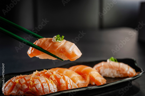 Blowtorcherd salmon onigiri on chopsticks.
