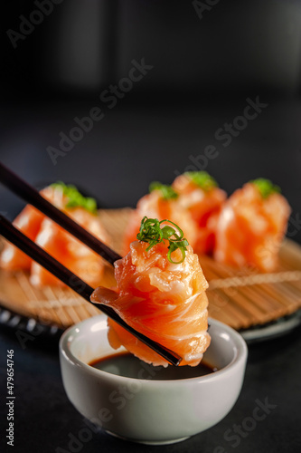 Salmon Jhow sushi on chopsticks.
