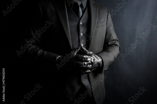 Portrait of Elegant Gentleman in Dark Suit and Leather Gloves on Black Background. Vintage Style and Retro Fashion.