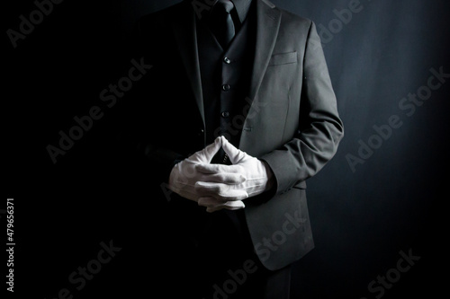 Portrait of Man in Dark Suit and White Gloves Standing on Black Background. Elegant Service and Professional Hospitality.