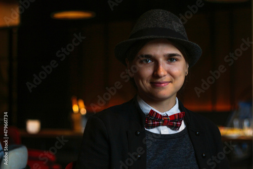 Woman wearing in british or english style clothes. Masculine woman. Young smiling woman wearing hat, bow tie and classic suit indoor. Happy freedom women. Nerdy person. Elegant style