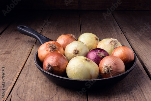 A frying pan with onions on a background of antique board. High quality photo