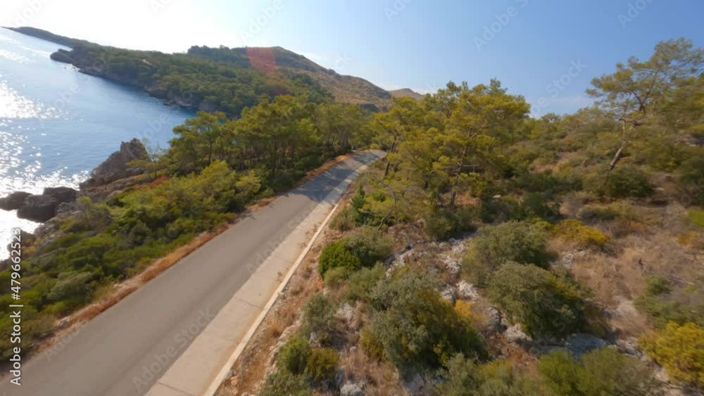 FPV video, view from above, aerial view from an FPV drone flying at high speed over a coastline with a road by a blue, crystal clear water. Pine forests and deep blue sky by the seaside. Mediterranean FPV video, view from above, aerial view from an FPV drone flying at high speed over a coastline with a road by a blue, crystal clear water. Pine forests and deep blue sky by the seaside. Mediterranean