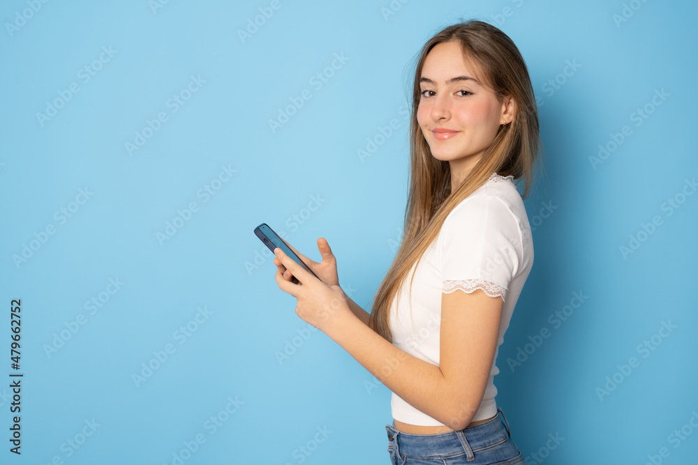 Beautiful girl using smartphone standing isolated over blue background. Beautiful girl using smartphone standing isolated over blue background.
