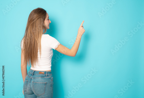 Backside view of young woman with long hair writing over green background.