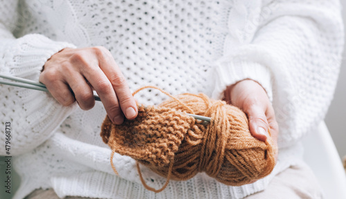 Women's hands are engaged in knitting needlework. Threads for knitting, knitting needles close-up, selective soft focus. Hobby home needlework knitting