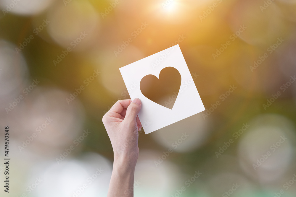 White paper with cut heart shape in a hand White paper with cut heart shape in a hand