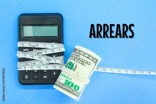 banknotes and calculators wrapped with measuring tape with the word arrears. the concept of arrears