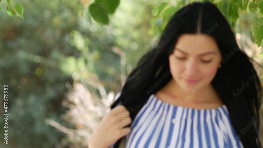 Beautiful happy young woman in love walks among green leaves on birch branches. Pleasant lady smiles and enjoys nature. Girl walking park. Stylish long haired female. Beautiful sunny warm day. Blurred Beautiful happy young woman in love walks among green leaves on birch branches. Pleasant lady smiles and enjoys nature. Girl walking park. Stylish long haired female. Beautiful sunny warm day. Blurred