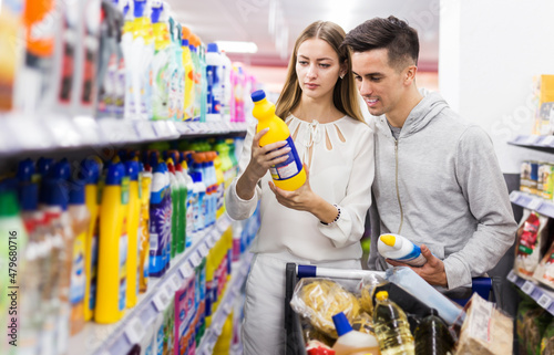 Young family couple making purchases together, buying household chemicals in store