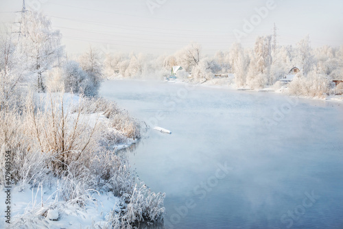 Trees on the banks of the river in white snow frost in the Moscow region on a winter sunny evening