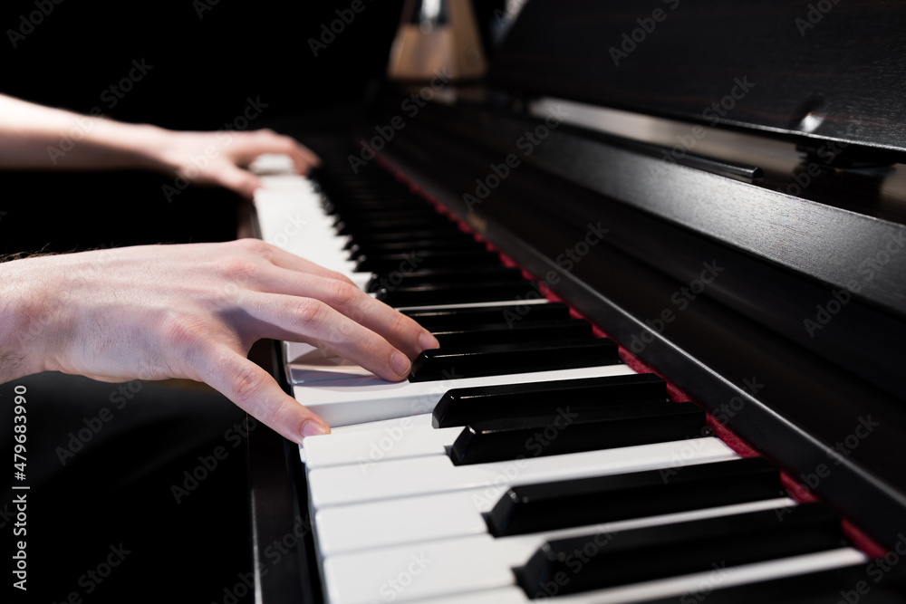 Fototapeta premium Close up of a piano player's hands. Person playing the keyboard musical instrument