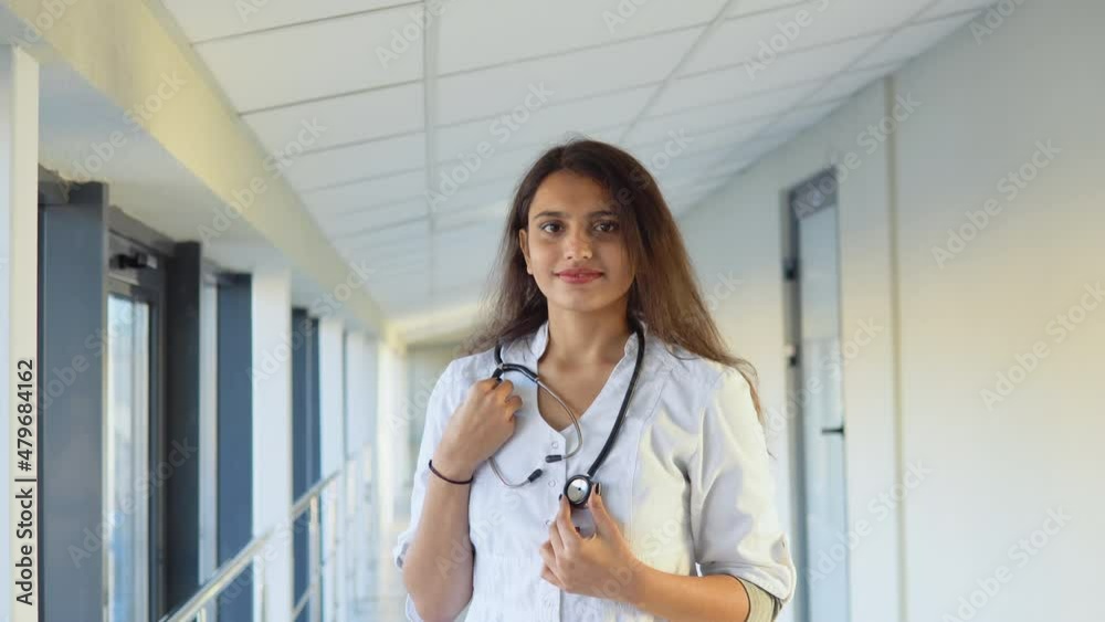 Friendly happy indian woman physician or nurse professional general practitioner posing with stethoscope looking at camera in clinic. Smiling young female doctor close up portrait Friendly happy indian woman physician or nurse professional general practitioner posing with stethoscope looking at camera in clinic. Smiling young female doctor close up portrait