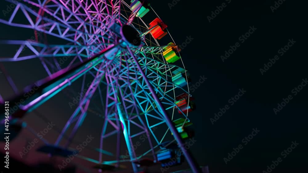 A colourful Ferris wheel spinning slowly during a dark night in an endless loop