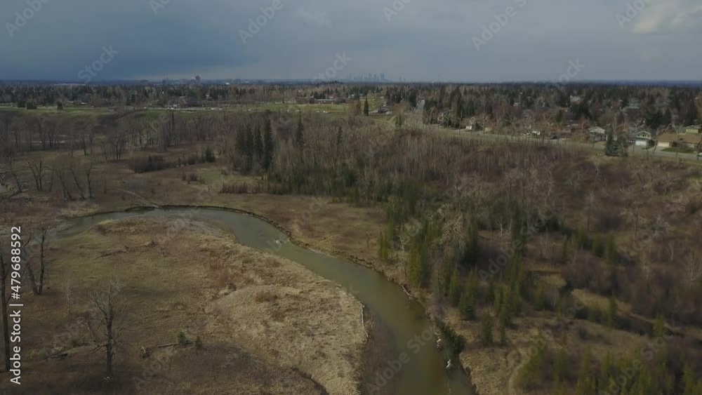 A creek in nature tilting up to a busy road and city skyline on the horizon A creek in nature tilting up to a busy road and city skyline on the horizon