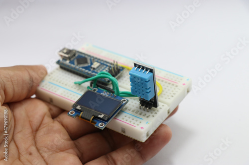 Humidity and temperature sensing module for arduino projects with OLED circuit on a breadboard held in hand showing the concept of creative idea
