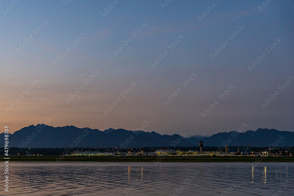Vancouver International Airport YVR at dusk reflecting in the calm waters of the Fraser River
